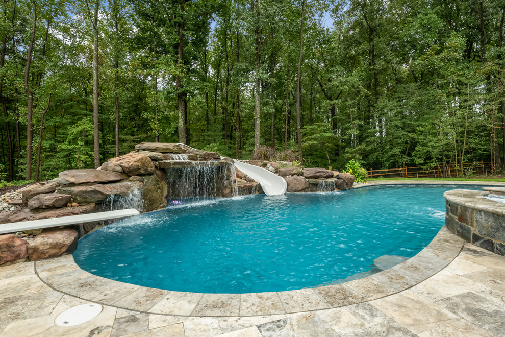 Foto di una grande piscina naturale classica a "C" dietro casa con un acquascivolo e piastrelle