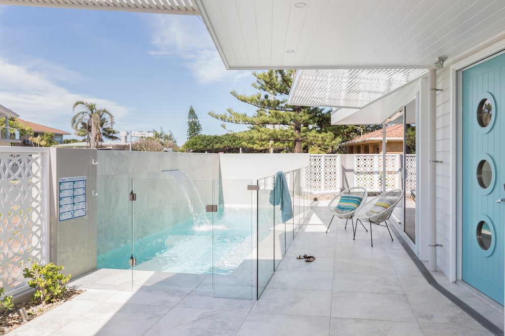 Esempio di una piscina monocorsia costiera rettangolare di medie dimensioni e davanti casa con fontane e lastre di cemento