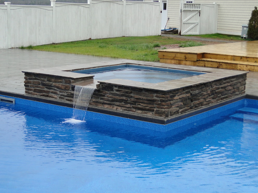 Diseño de piscinas y jacuzzis modernos grandes en forma de L en patio trasero con suelo de hormigón estampado