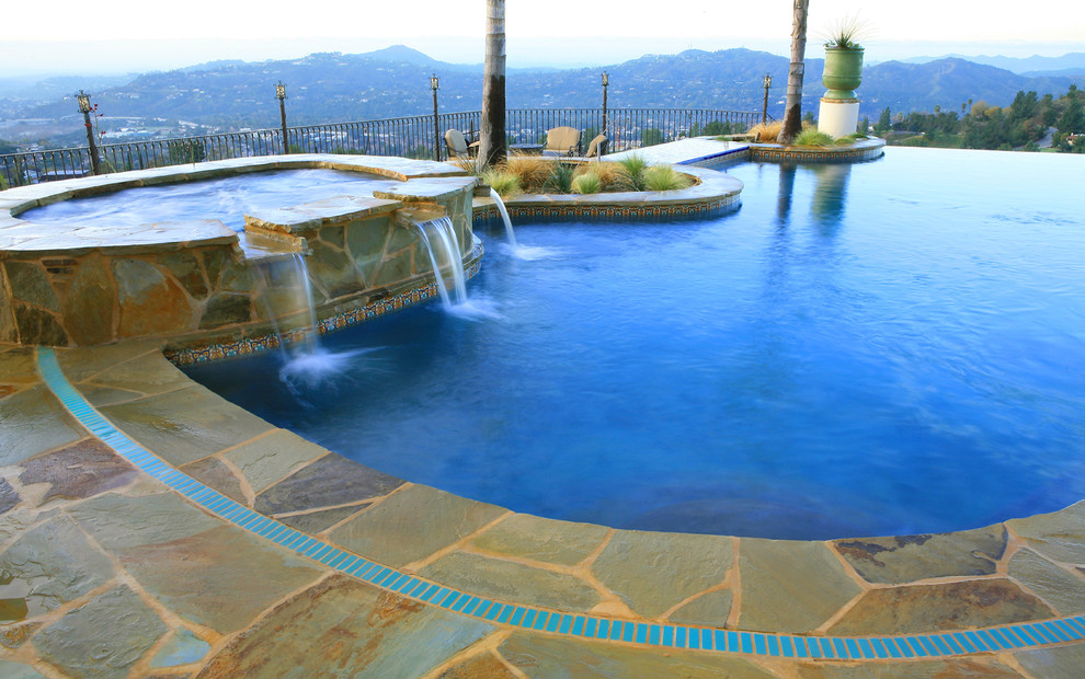 Inspiration for a large mediterranean backyard stone and custom-shaped infinity pool fountain remodel in Los Angeles