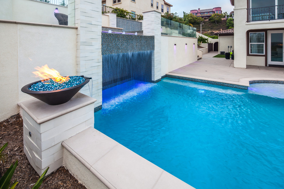 Medium sized modern back rectangular swimming pool in San Diego with a water feature and concrete slabs.