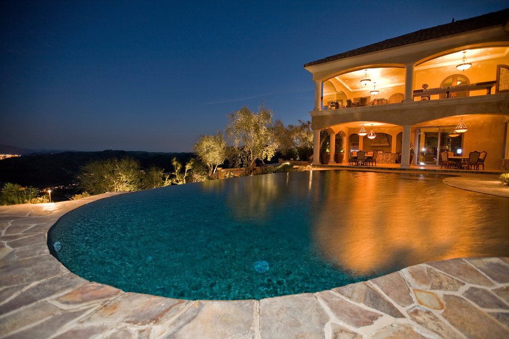 Inspiration pour une grande piscine arrière et à débordement méditerranéenne sur mesure avec des pavés en pierre naturelle.