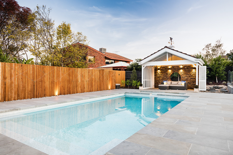 Photo of a large contemporary back rectangular swimming pool in Melbourne with a pool house and natural stone paving.
