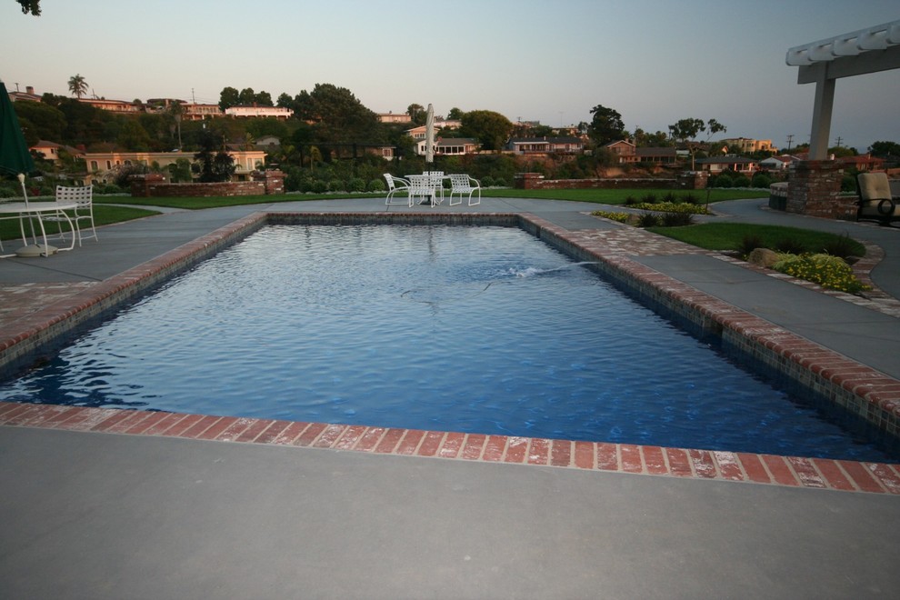 Design ideas for a large eclectic back rectangular lengths swimming pool in San Diego with a pool house and concrete slabs.