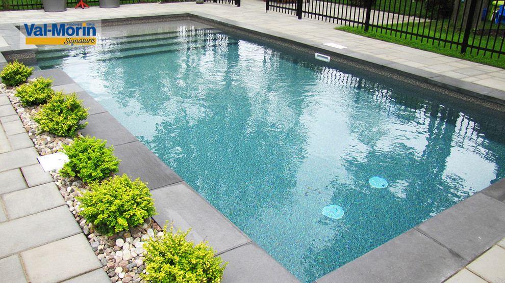 Photo of a large modern back rectangular swimming pool with brick paving.