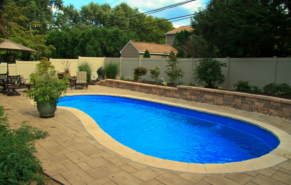 Пример оригинального дизайна: бассейн среднего размера, в форме фасоли на заднем дворе в современном стиле с мощением тротуарной плиткой