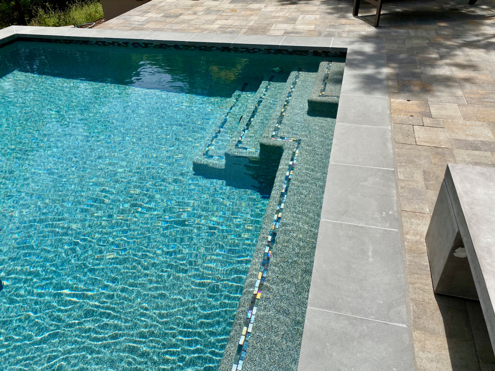 Diseño de piscina alargada minimalista extra grande rectangular en patio trasero con paisajismo de piscina y adoquines de hormigón