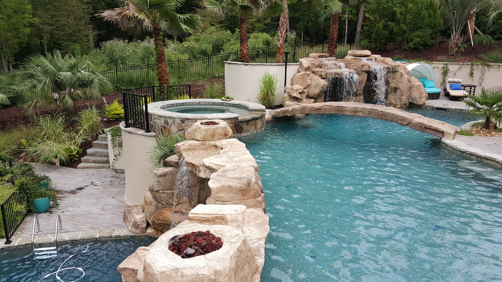 Inspiration för en stor tropisk anpassad pool på baksidan av huset, med vattenrutschkana och naturstensplattor