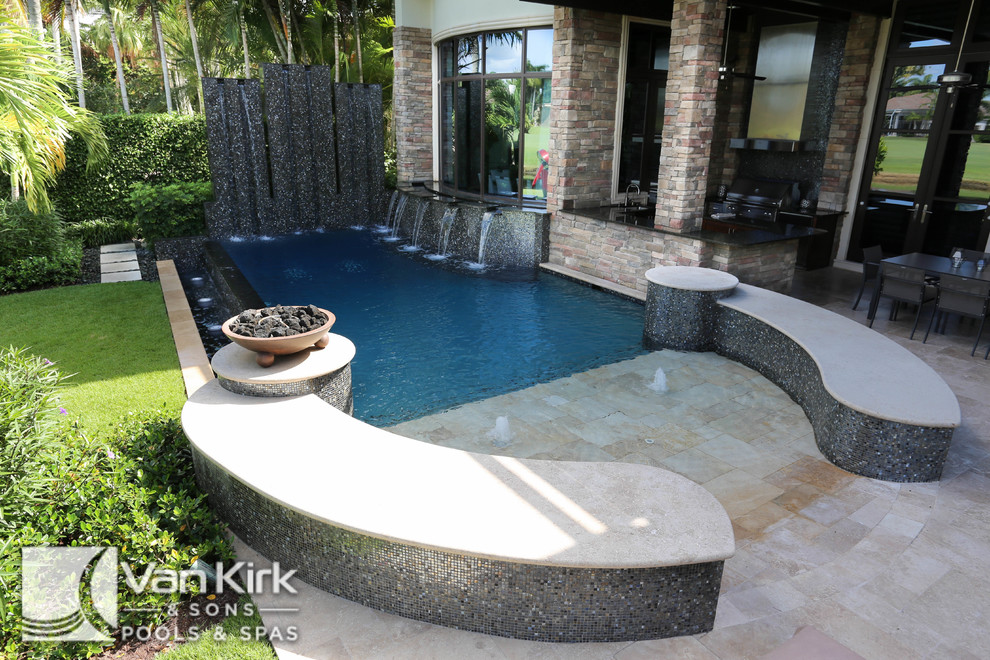 Design ideas for a small contemporary back custom shaped swimming pool in Miami with a water feature and natural stone paving.
