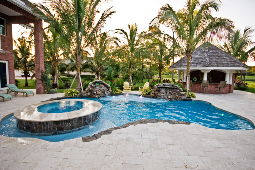 Mid-sized island style backyard stone and custom-shaped hot tub photo in Miami