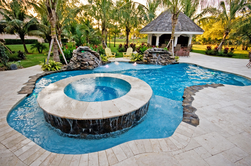 This is an example of a medium sized world-inspired back custom shaped hot tub in Miami with natural stone paving.
