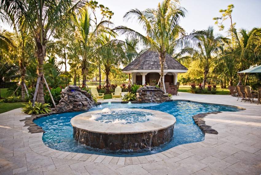 Foto på en mellanstor tropisk pool på baksidan av huset, med spabad och naturstensplattor