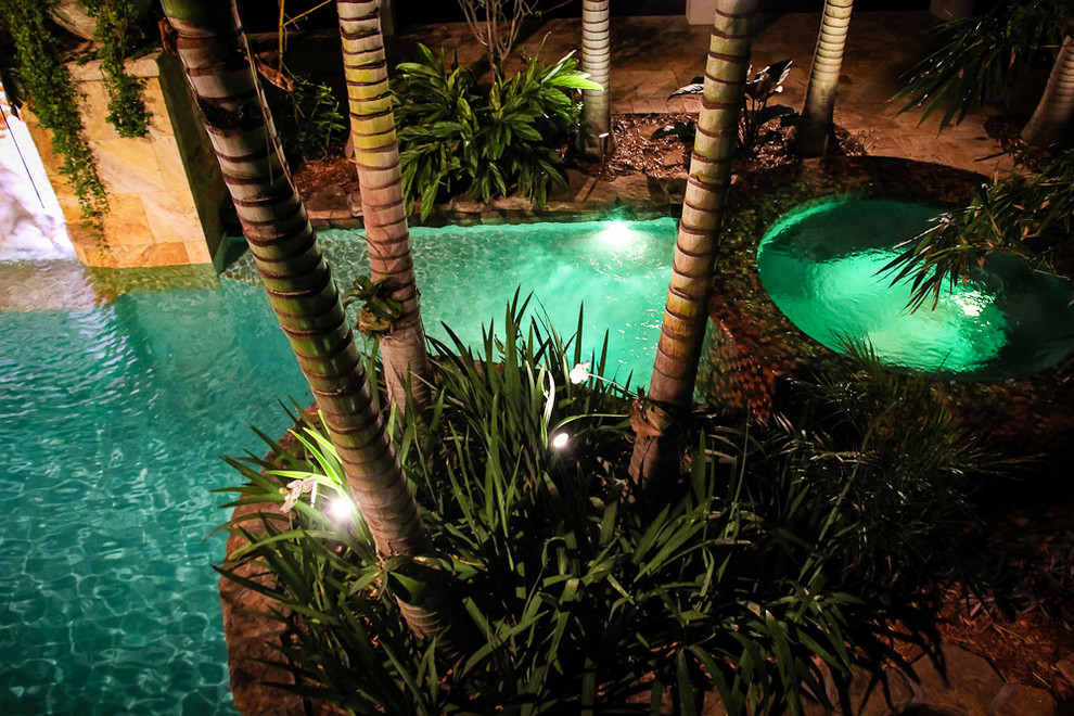 Diseño de piscina con fuente alargada exótica extra grande a medida en patio trasero con adoquines de piedra natural