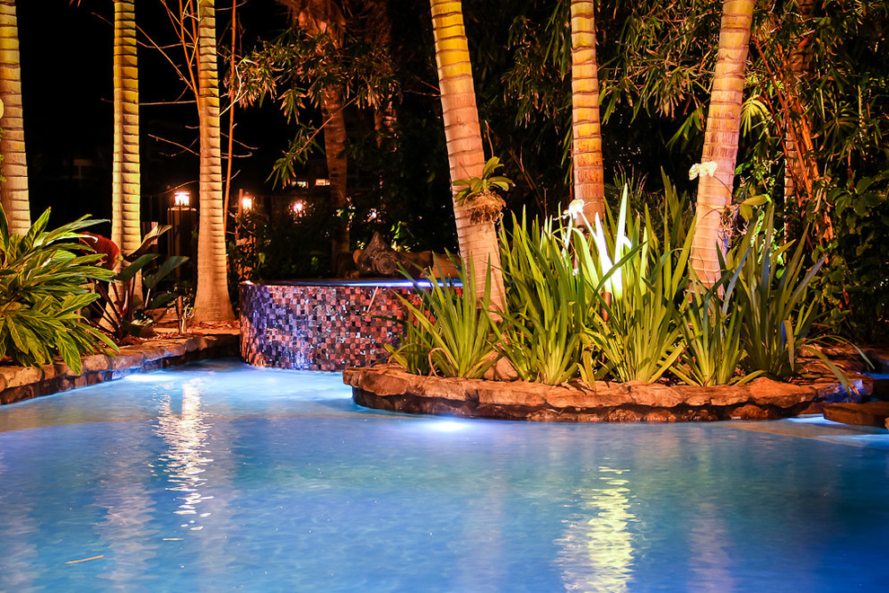 Foto de piscina con fuente alargada tropical extra grande a medida en patio trasero con adoquines de piedra natural