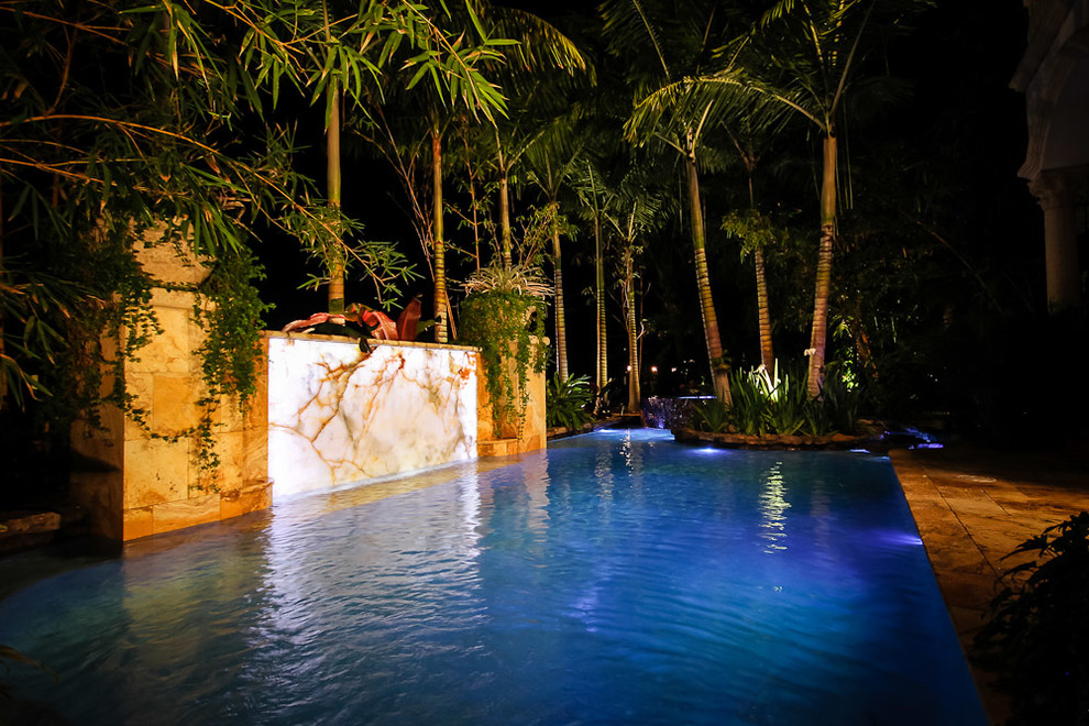 Modelo de piscina con fuente alargada exótica extra grande a medida en patio trasero con adoquines de piedra natural