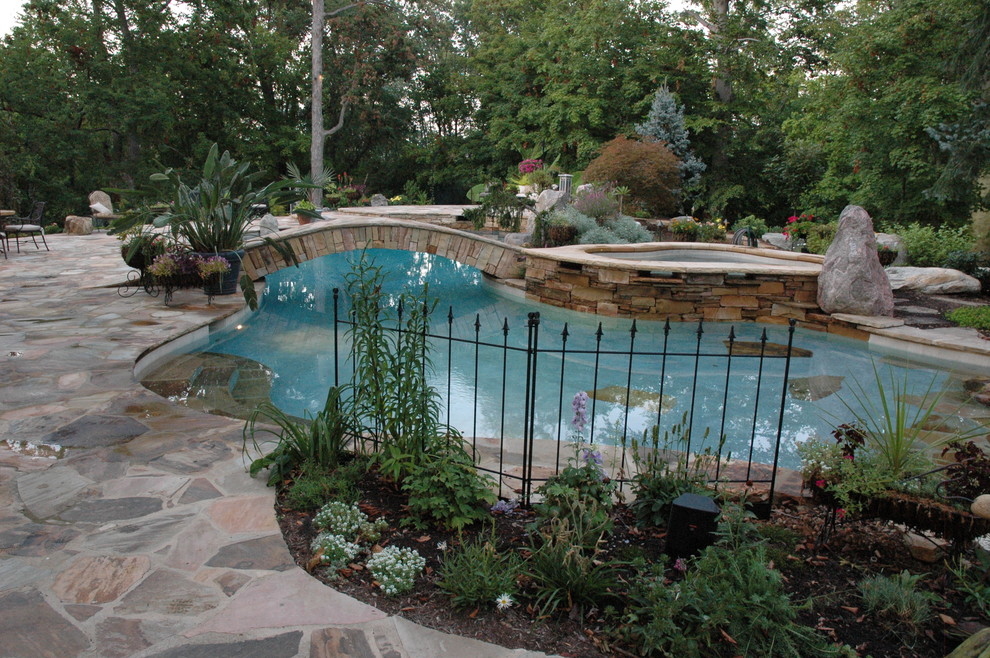 Cette photo montre une grande piscine naturelle et arrière éclectique sur mesure avec des pavés en pierre naturelle.