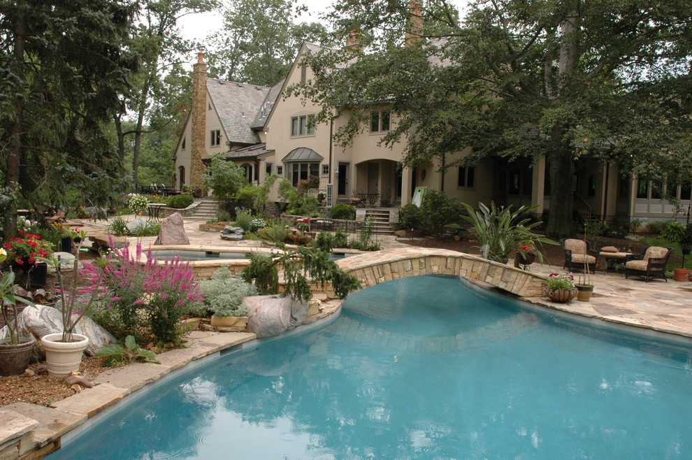Immagine di una grande piscina naturale eclettica personalizzata dietro casa con pavimentazioni in pietra naturale