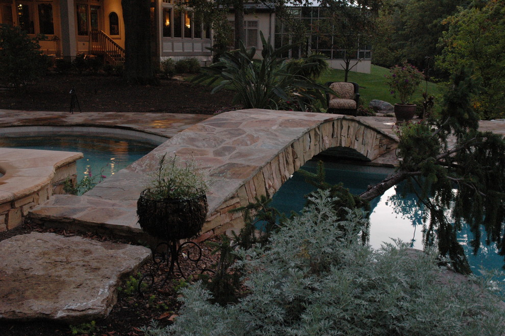 Immagine di una grande piscina naturale boho chic personalizzata dietro casa con pavimentazioni in pietra naturale