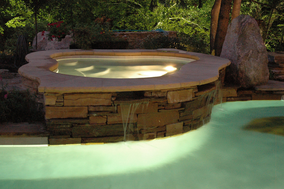 Immagine di una grande piscina naturale bohémian personalizzata dietro casa con una vasca idromassaggio e pavimentazioni in pietra naturale