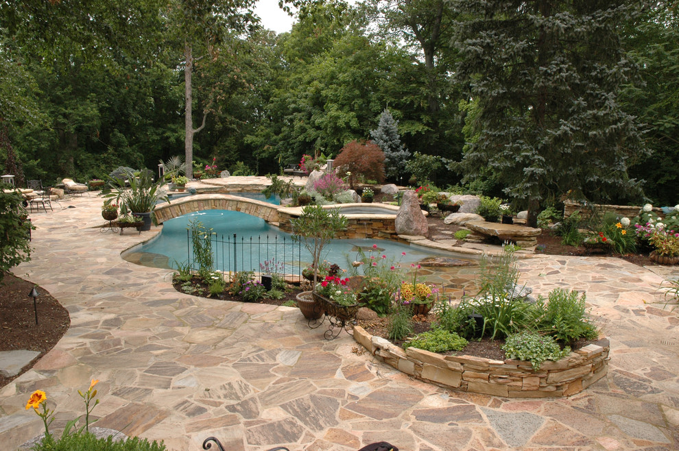 Esempio di una grande piscina naturale tradizionale personalizzata dietro casa con pavimentazioni in pietra naturale