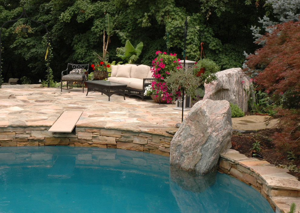 Стильный дизайн: большой естественный бассейн произвольной формы на заднем дворе в стиле фьюжн с покрытием из каменной брусчатки - последний тренд