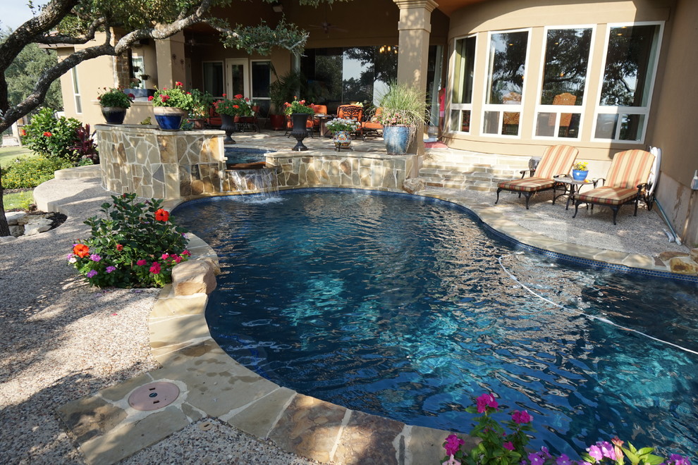 Immagine di una grande piscina stile rurale a "C" dietro casa con una vasca idromassaggio e pavimentazioni in pietra naturale