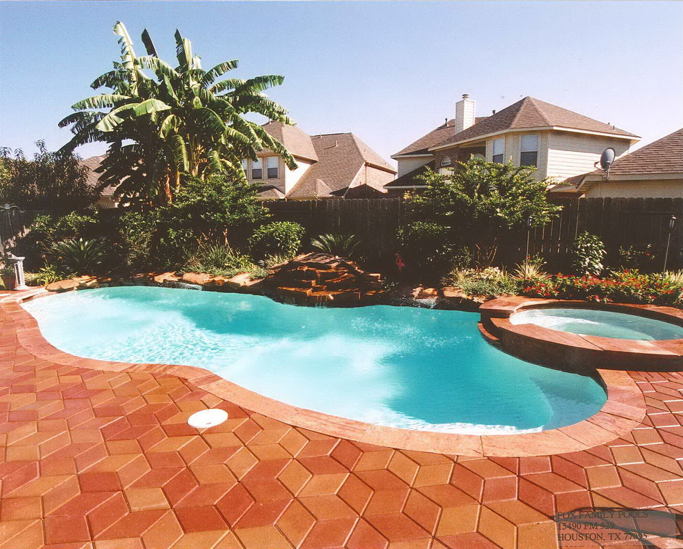 Mittelgroßer Schwimmteich hinter dem Haus in individueller Form mit Wasserspiel und Natursteinplatten in Houston