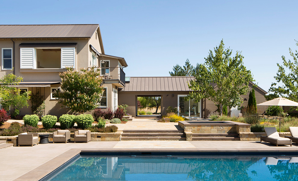 Diseño de piscina de estilo de casa de campo en patio trasero con adoquines de piedra natural