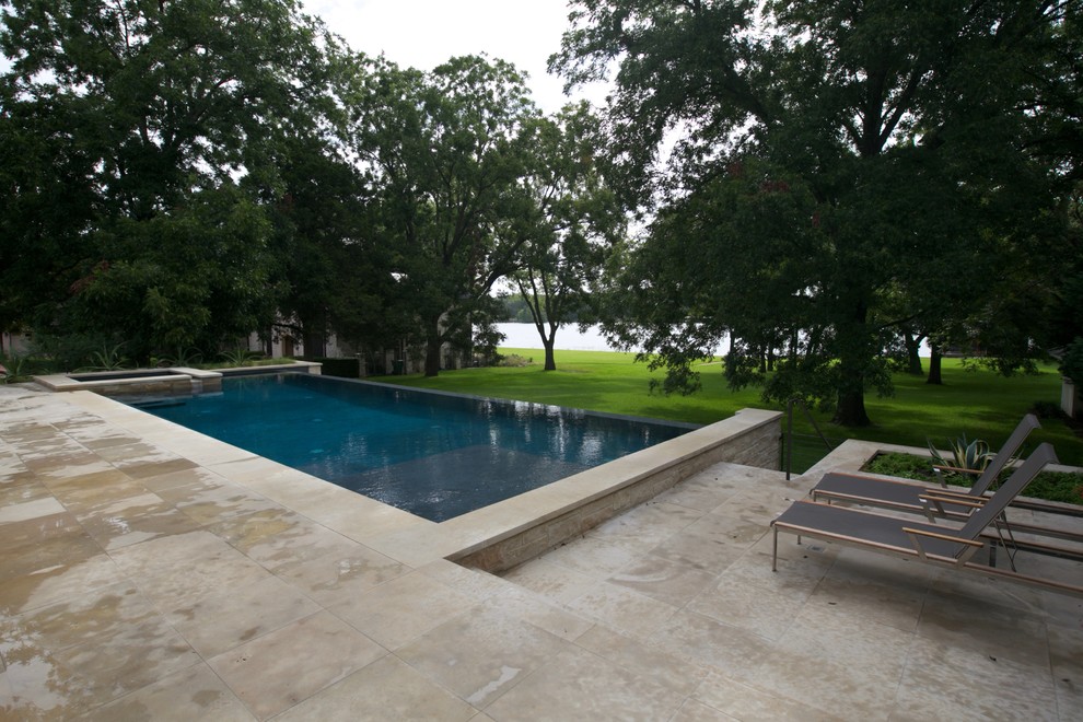 Example of a large trendy backyard stone and rectangular infinity pool fountain design in Austin