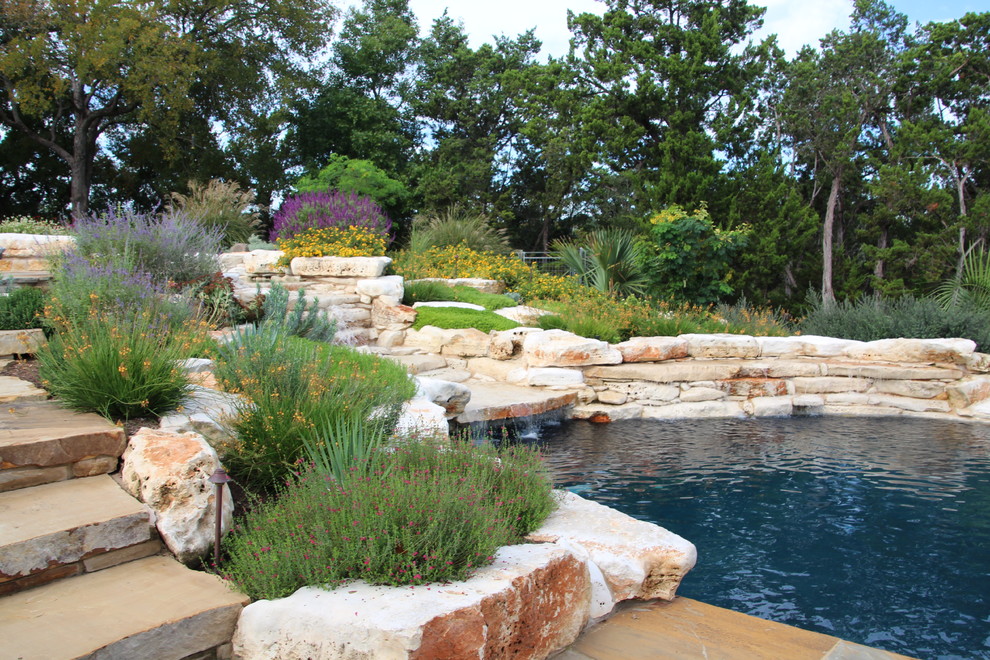 Foto de piscina con fuente alargada clásica renovada de tamaño medio redondeada en patio trasero con adoquines de piedra natural