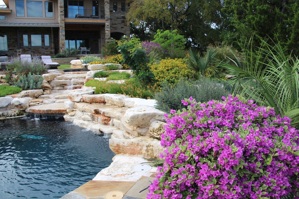 Diseño de piscina con fuente alargada clásica renovada de tamaño medio redondeada en patio trasero con adoquines de piedra natural