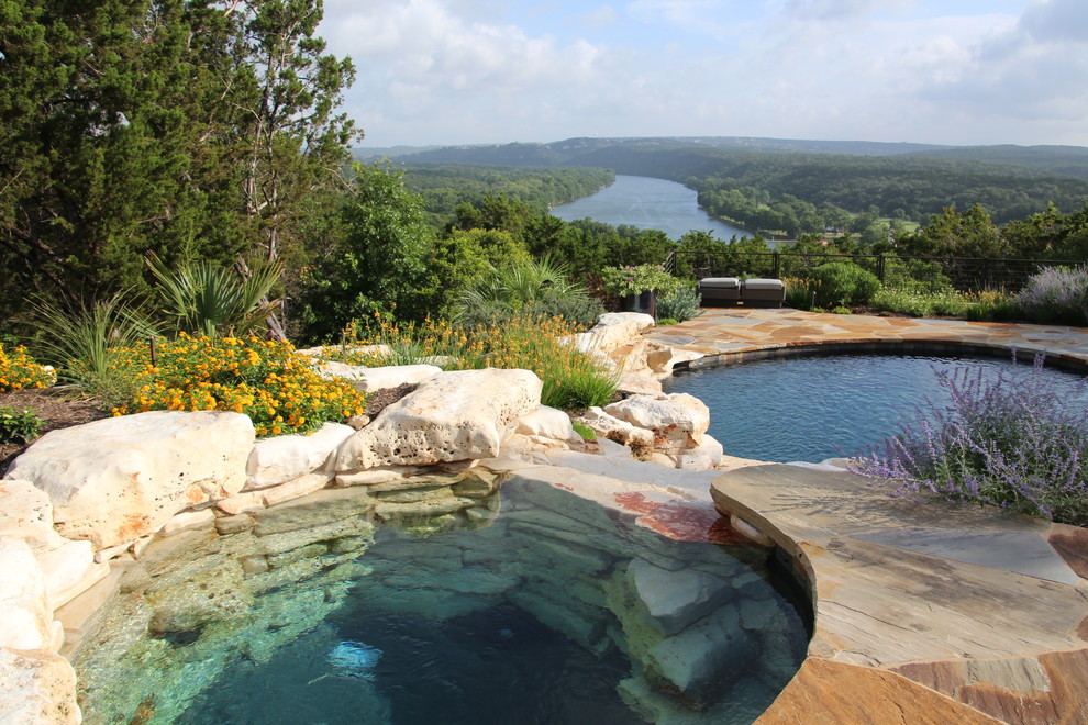 Foto de piscina con fuente alargada contemporánea grande redondeada en patio trasero con adoquines de piedra natural