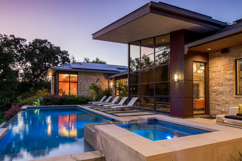 На фото: бассейн-инфинити среднего размера на заднем дворе в стиле модернизм с джакузи с
