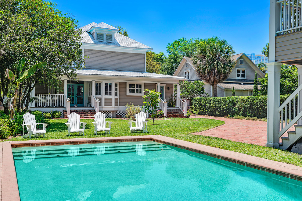 Photo of a classic back rectangular swimming pool in Orlando with a pool house and brick paving.