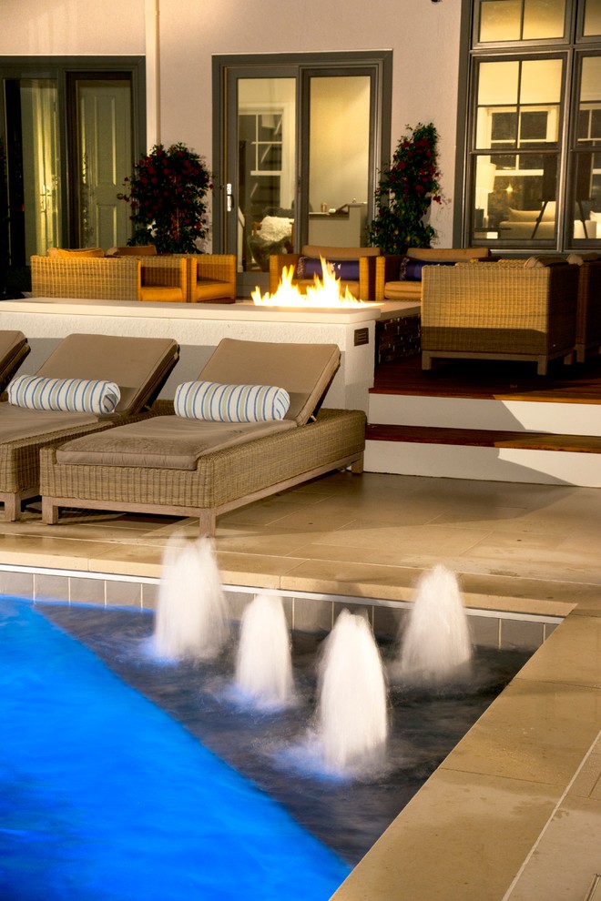Modelo de piscina con fuente alargada tradicional pequeña rectangular en patio trasero con adoquines de piedra natural