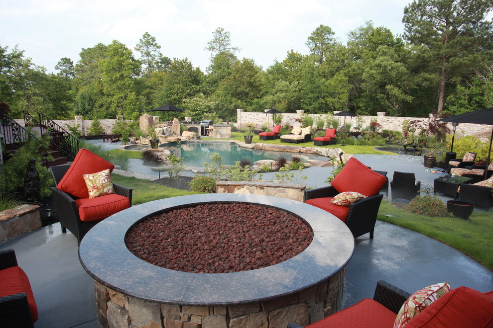 Large eclectic back custom shaped natural swimming pool in Other with a water feature and natural stone paving.