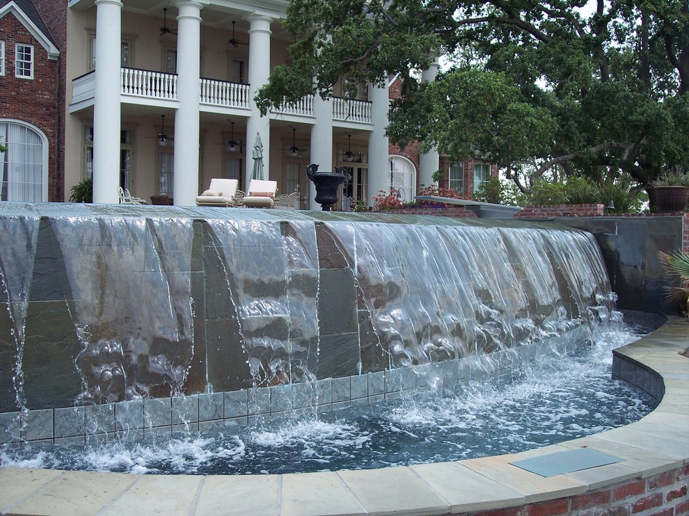 Пример оригинального дизайна: бассейн-инфинити среднего размера, произвольной формы на заднем дворе в стиле неоклассика (современная классика) с фонтаном и покрытием из каменной брусчатки