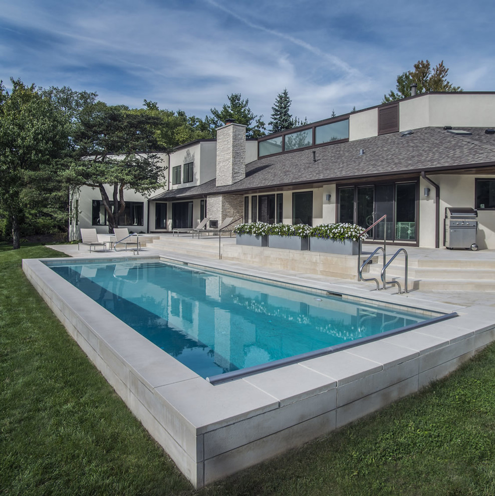 Imagen de piscina de tamaño medio rectangular en patio trasero con adoquines de piedra natural