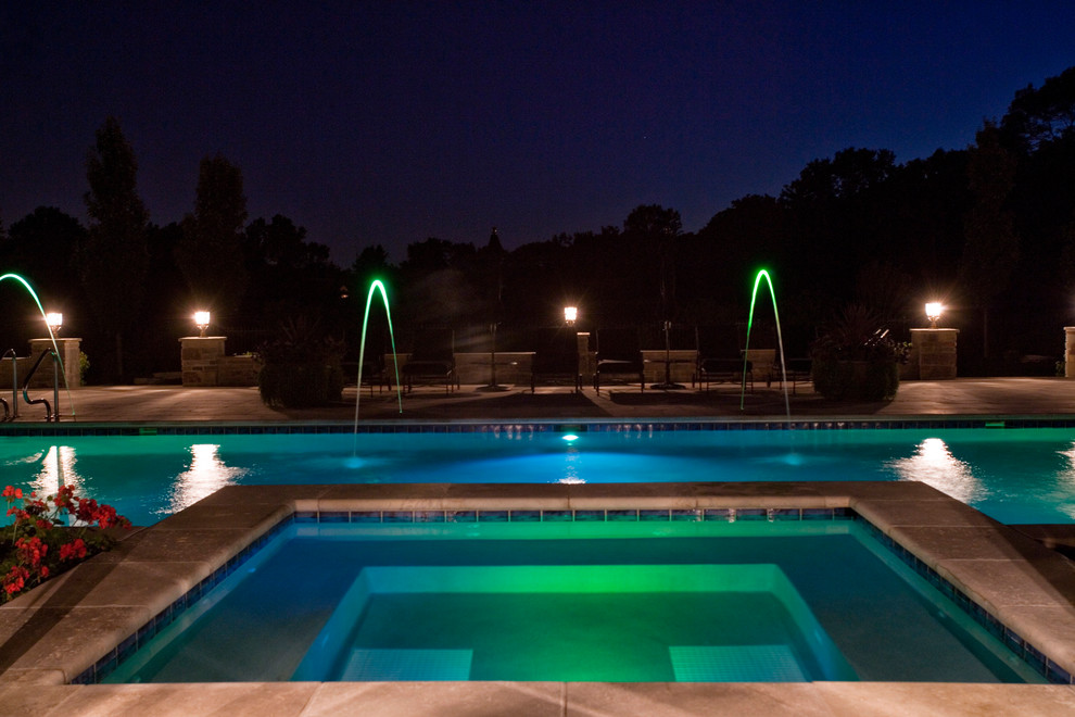 На фото: большой спортивный, прямоугольный бассейн на заднем дворе в классическом стиле с джакузи и покрытием из каменной брусчатки