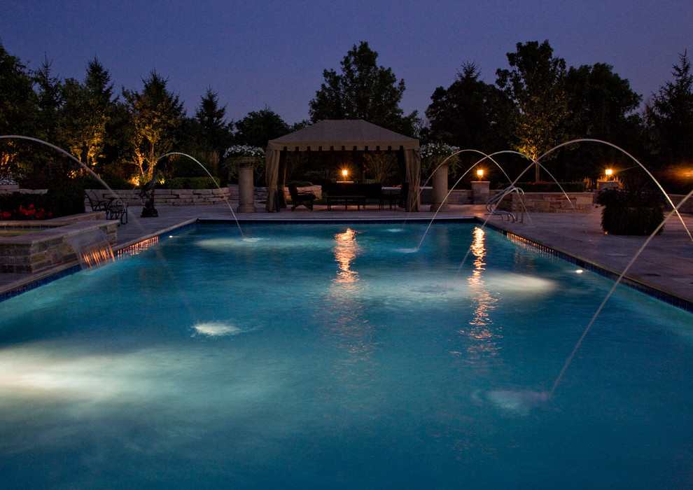Immagine di una grande piscina monocorsia classica rettangolare dietro casa con una vasca idromassaggio e pavimentazioni in pietra naturale