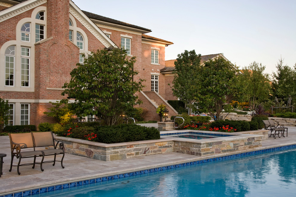 На фото: большой спортивный, прямоугольный бассейн на заднем дворе в классическом стиле с джакузи и покрытием из каменной брусчатки