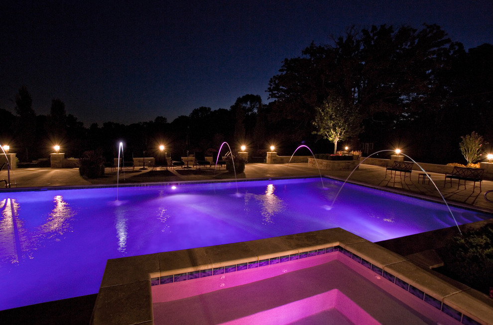 Ejemplo de piscinas y jacuzzis alargados clásicos grandes rectangulares en patio trasero con adoquines de piedra natural