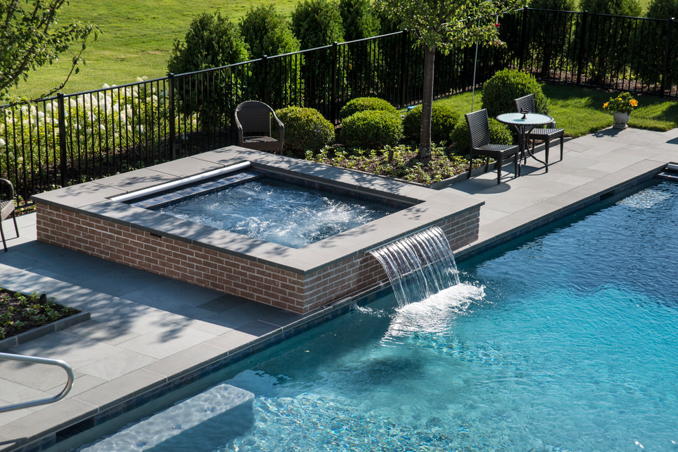 На фото: спортивный, прямоугольный бассейн среднего размера на заднем дворе в классическом стиле с джакузи и покрытием из каменной брусчатки