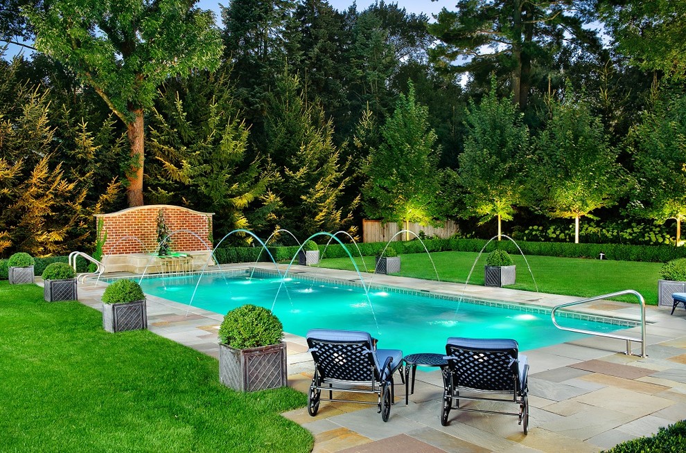 Imagen de piscina clásica de tamaño medio rectangular en patio trasero con adoquines de piedra natural