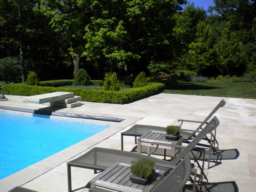 Ejemplo de piscina con tobogán alargada moderna grande rectangular en patio trasero con suelo de baldosas