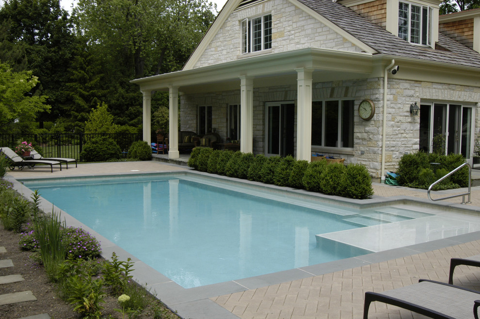 Photo of a small traditional side yard l-shaped lap pool in Chicago with concrete pavers.