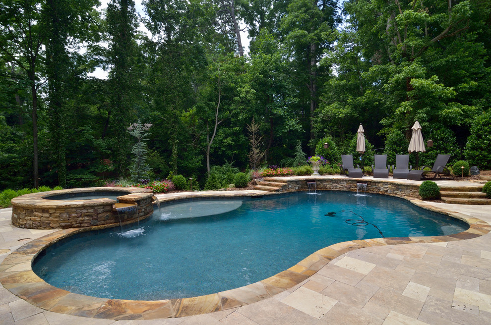 Cette image montre une grande piscine naturelle et arrière design sur mesure avec un bain bouillonnant et des pavés en pierre naturelle.