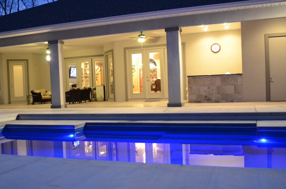 Ispirazione per una piscina a sfioro infinito mediterranea rettangolare di medie dimensioni e dietro casa con lastre di cemento