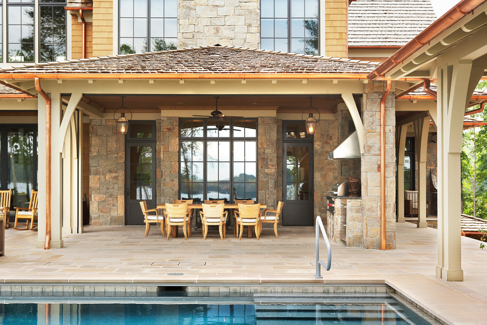 Ejemplo de piscina alargada clásica extra grande rectangular en patio trasero con adoquines de piedra natural