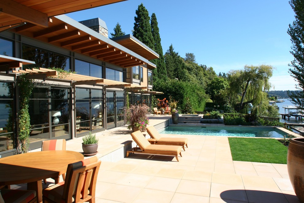 Esempio di una grande piscina monocorsia minimal rettangolare dietro casa con una vasca idromassaggio e pavimentazioni in cemento